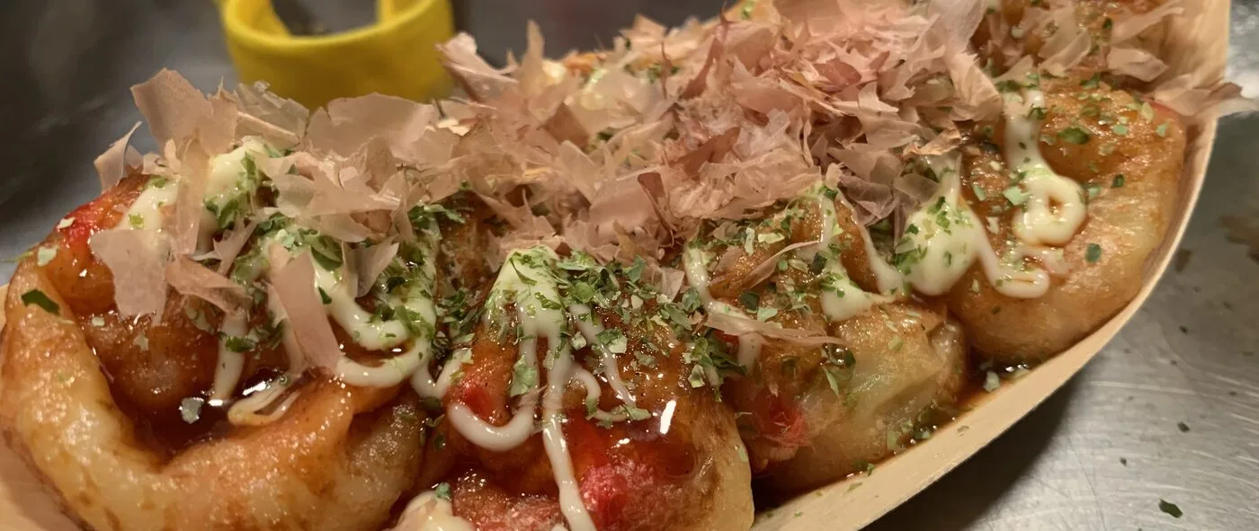 A boat of KarlsBalls takoyaki topped with bonito flakes, mayo and aonori