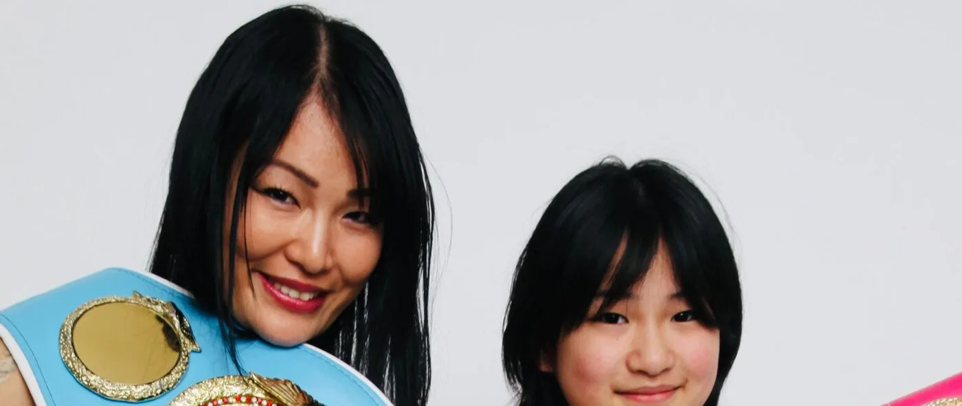 Miyo Yoshida with her world championship belts, her daughter beside her
