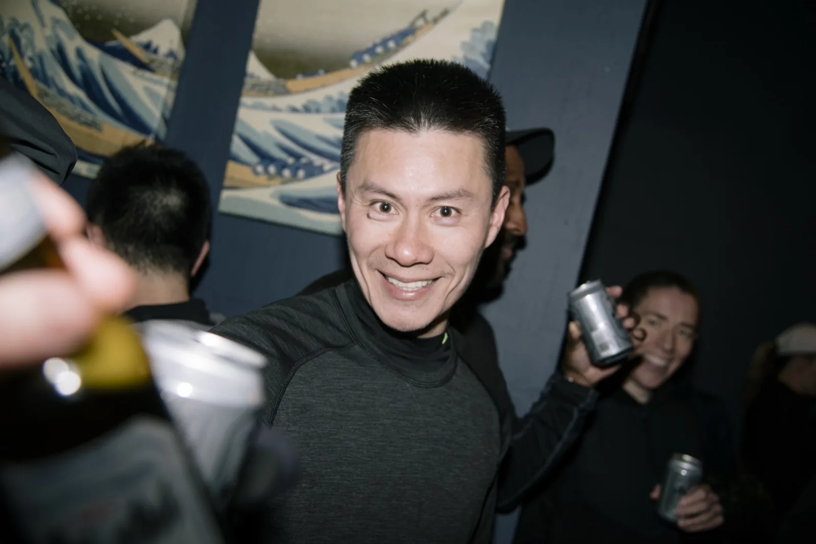 An OMRC runner raising an Asahi can inside Izakaya Juraku after a run, under the Great Wave banner